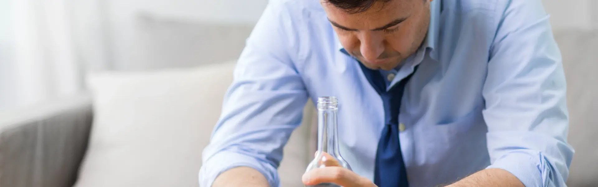 Mann sitzt deprimiert mit Alkoholflasche in der Hand